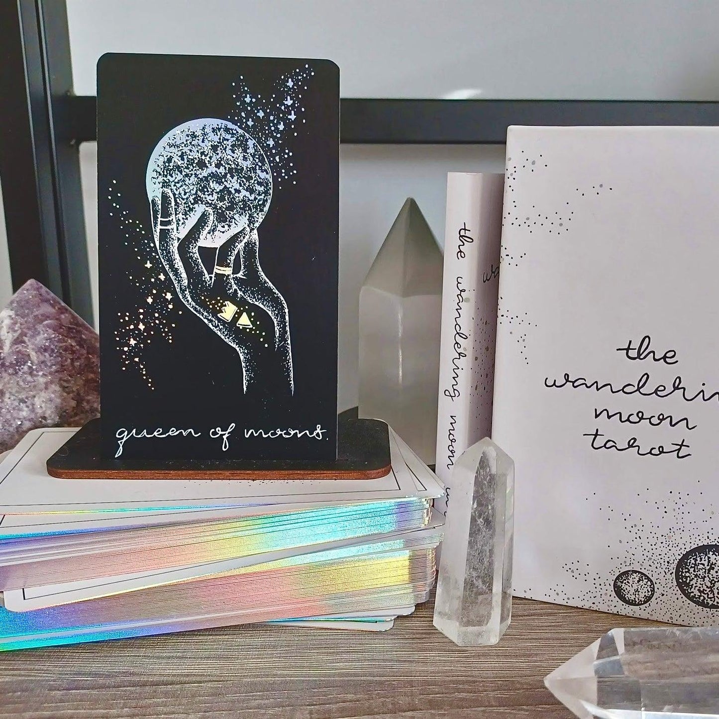 The Queen of Cups tarot card featured with indie tarot deck on bookshelf with crystals