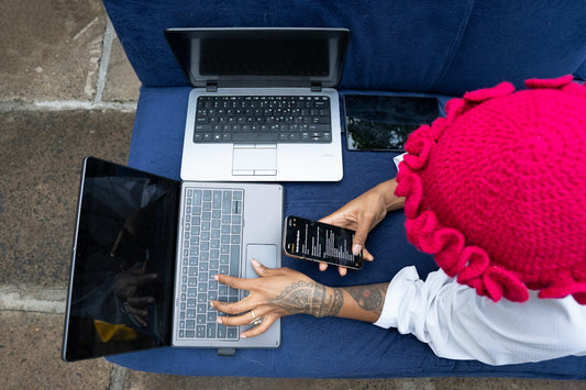 Person works on multiple laptops and a phone.