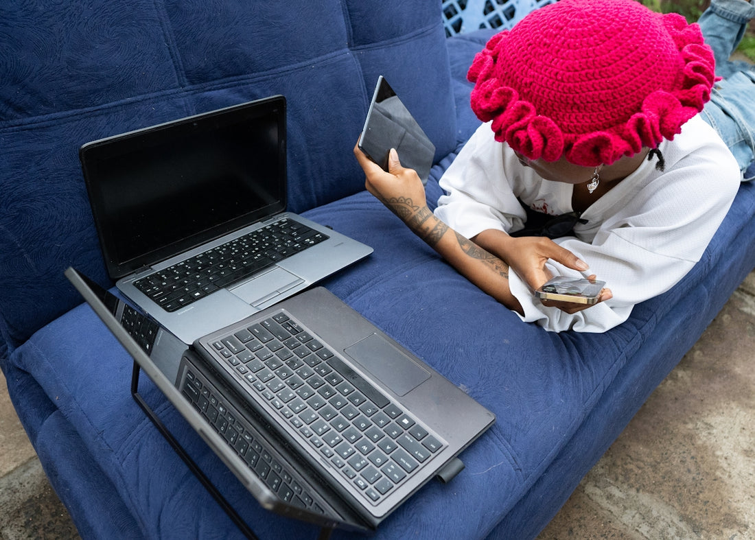 Person with laptops and phone on a blue couch