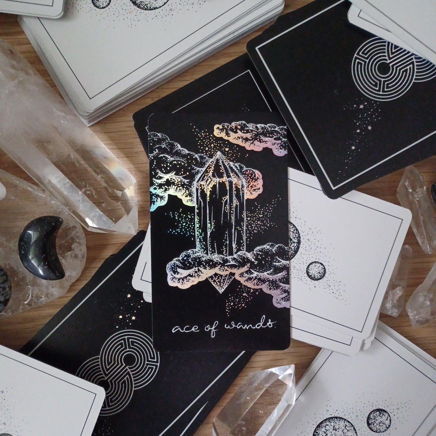 lone tarot card laying on face-down piles of tarot & oracle decks from The Wandering Moon Co. 