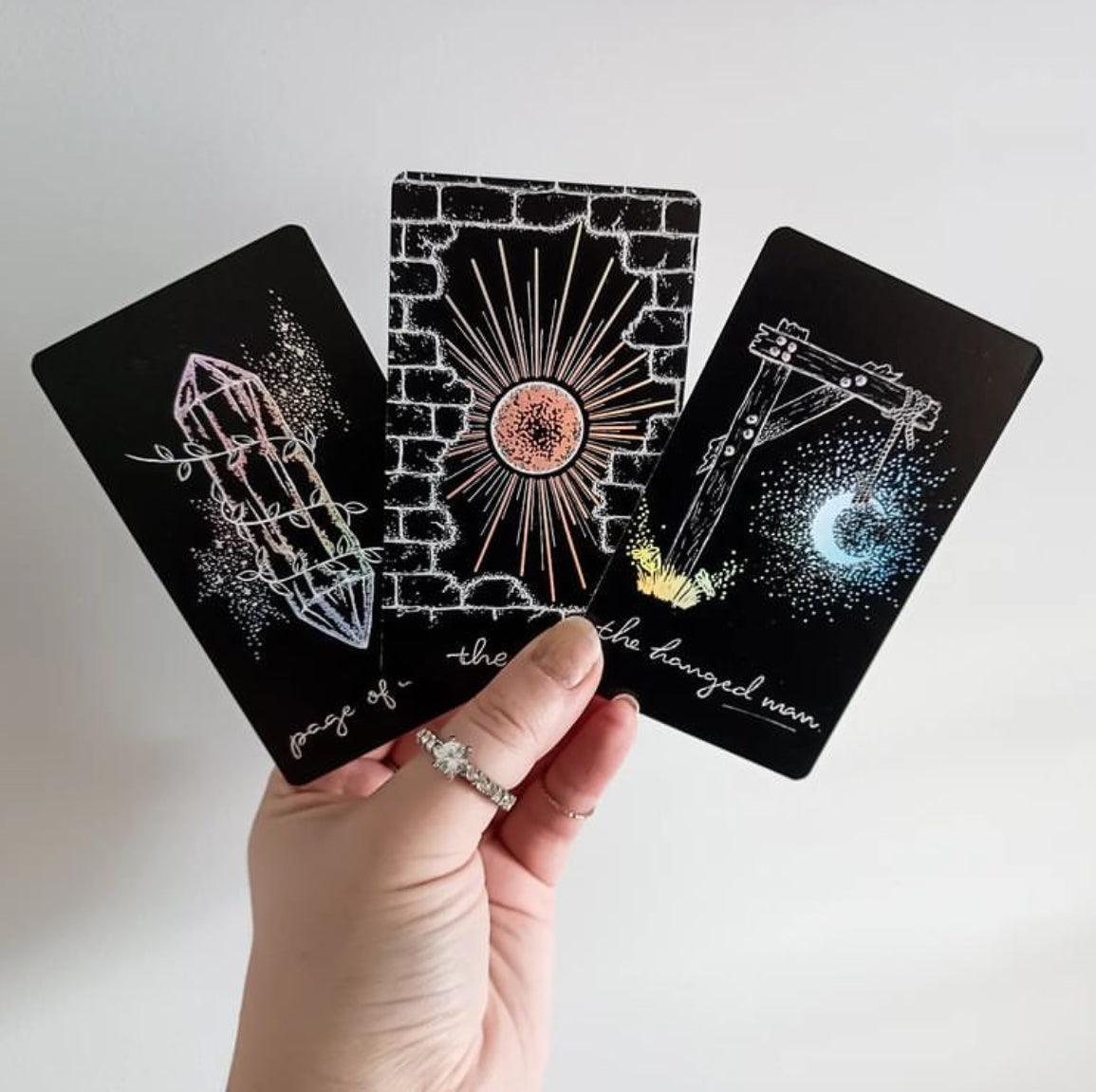 hand holding three tarot cards from Midnight Sky tarot, black cards with white illustrations